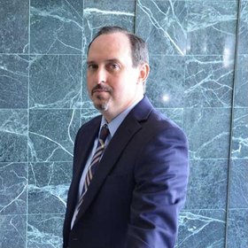 Justin Grove, attorney, in a navy suit and striped tie